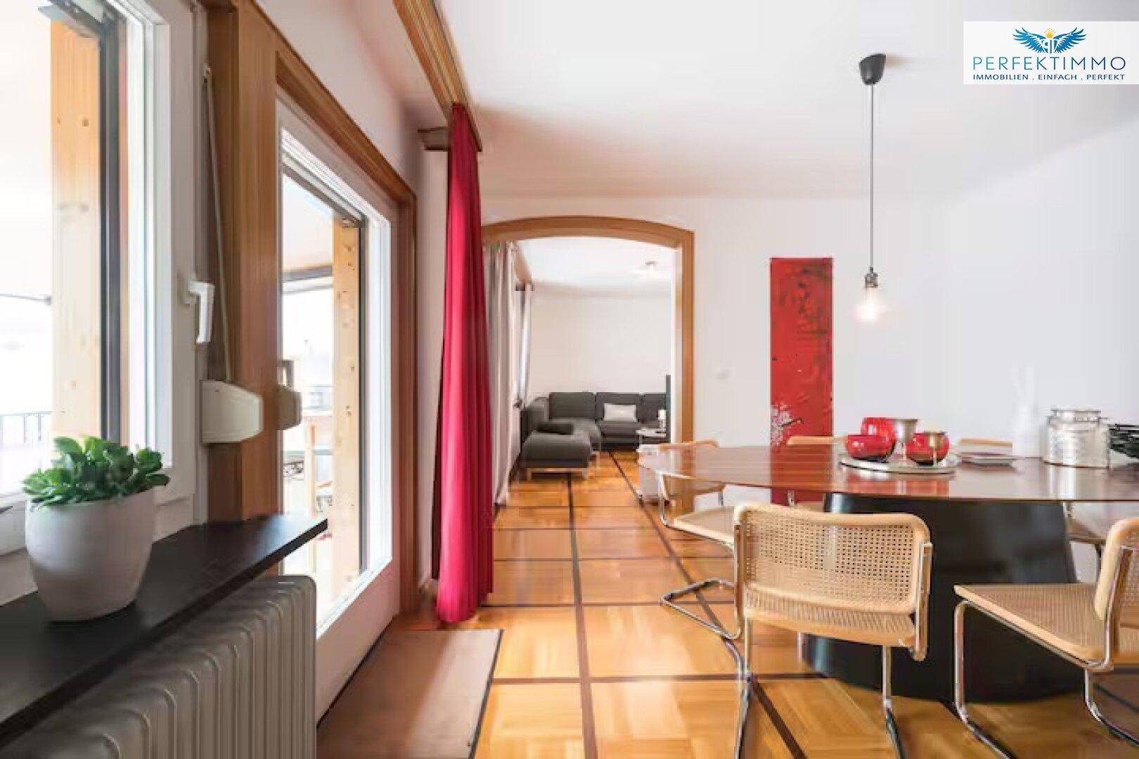 Offener Wohn- und Essbereich mit Parkettboden und Zugang zum Balkon.