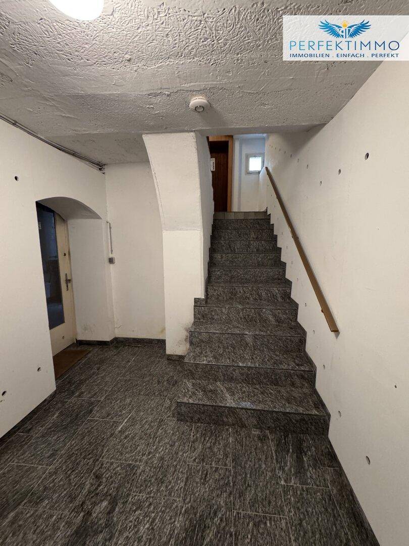 Kellertreppe mit Granitstufen und Handlauf, die in die oberen Etagen führt.