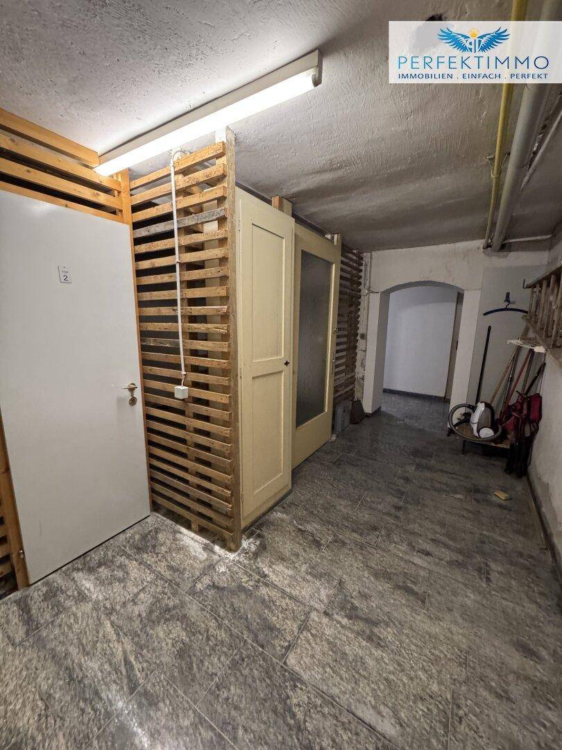 Hellerer Kellerbereich mit Holzverschlägen und Zugang zu weiteren Lagerräumen.