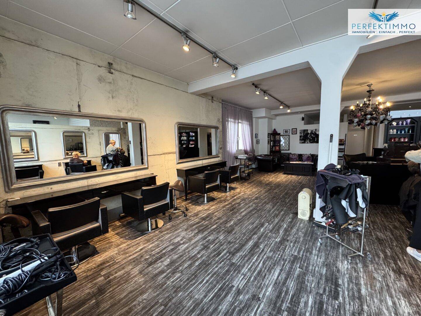 Friseurbereich mit Stylingstühlen, Spiegeln und Blick auf den Empfangsbereich.