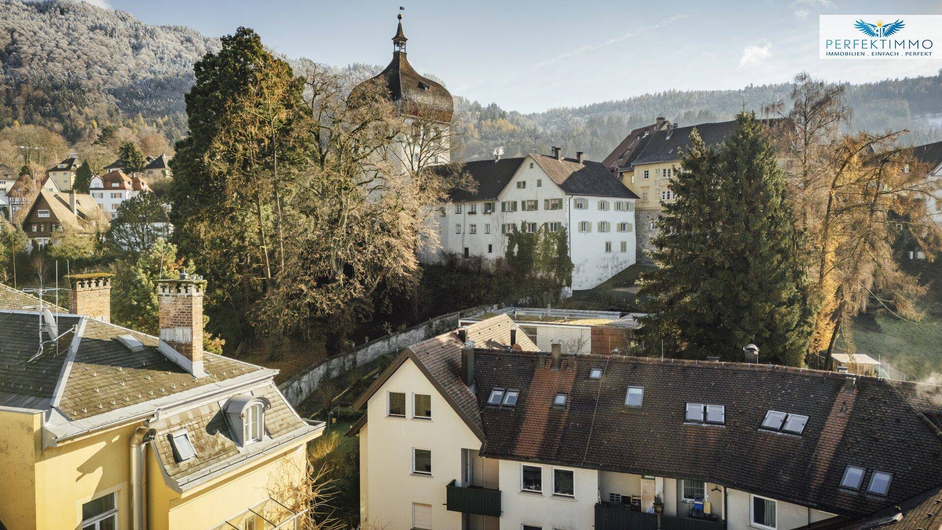 Malerischer Ausblick auf eine historische Stadt mit einem markanten Gebäude und grünen Hügeln.
