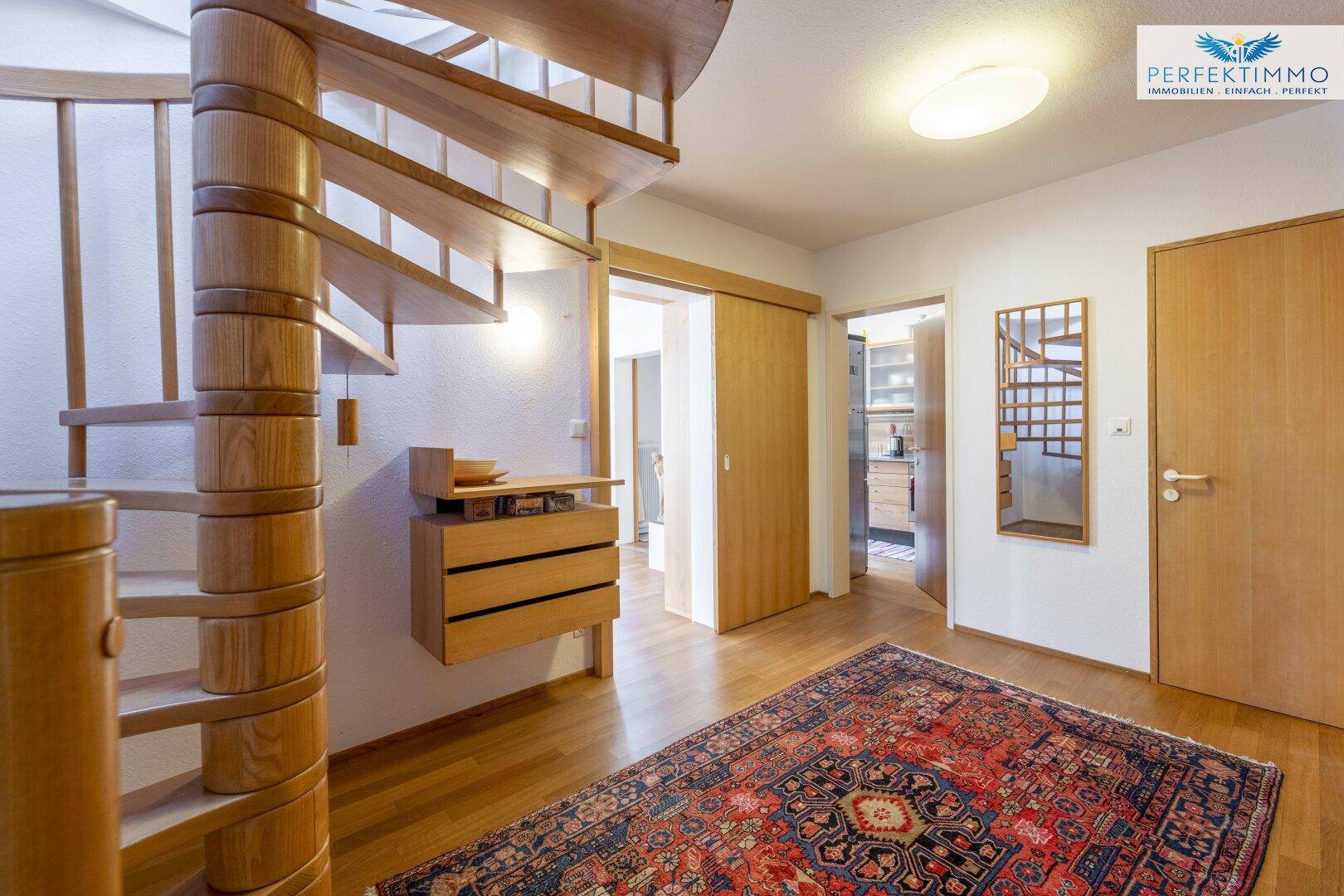 Geräumiger Flur mit einer eleganten Holzwendeltreppe und Zugang zu weiteren Räumen.