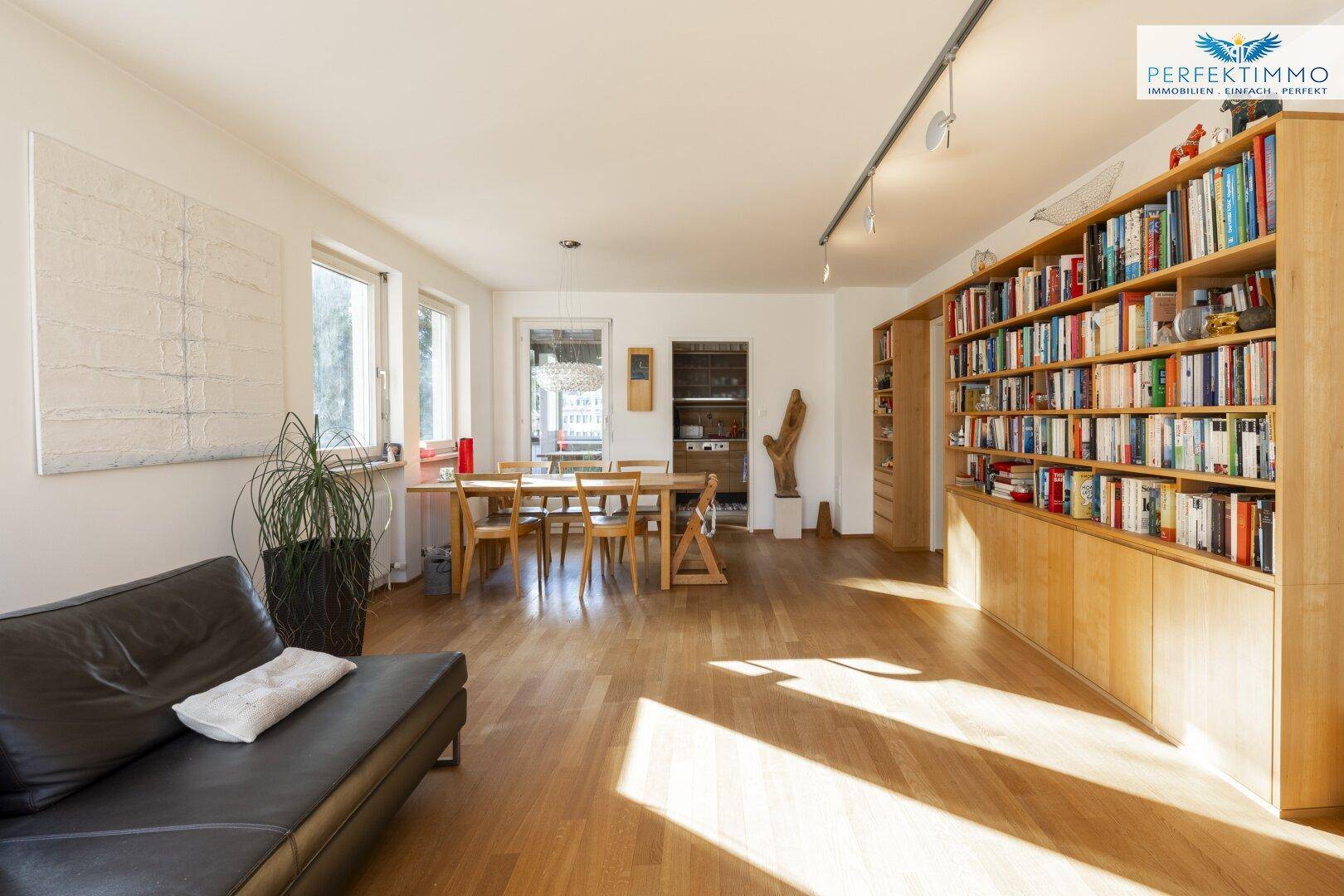 Geräumiger Wohn-Essbereich mit Holzboden, Esstisch und Sofa, hell durch große Fenster.