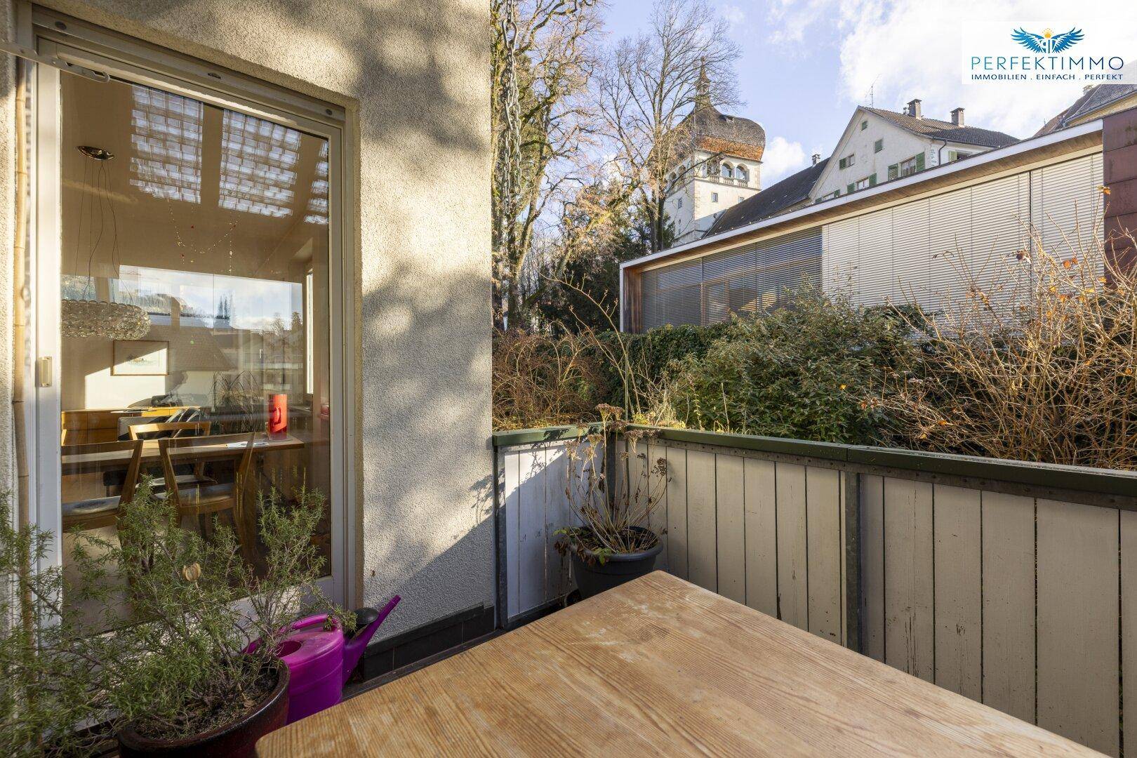 Balkon mit Blick in den Wohnbereich und auf den historischen Turm in der Ferne.