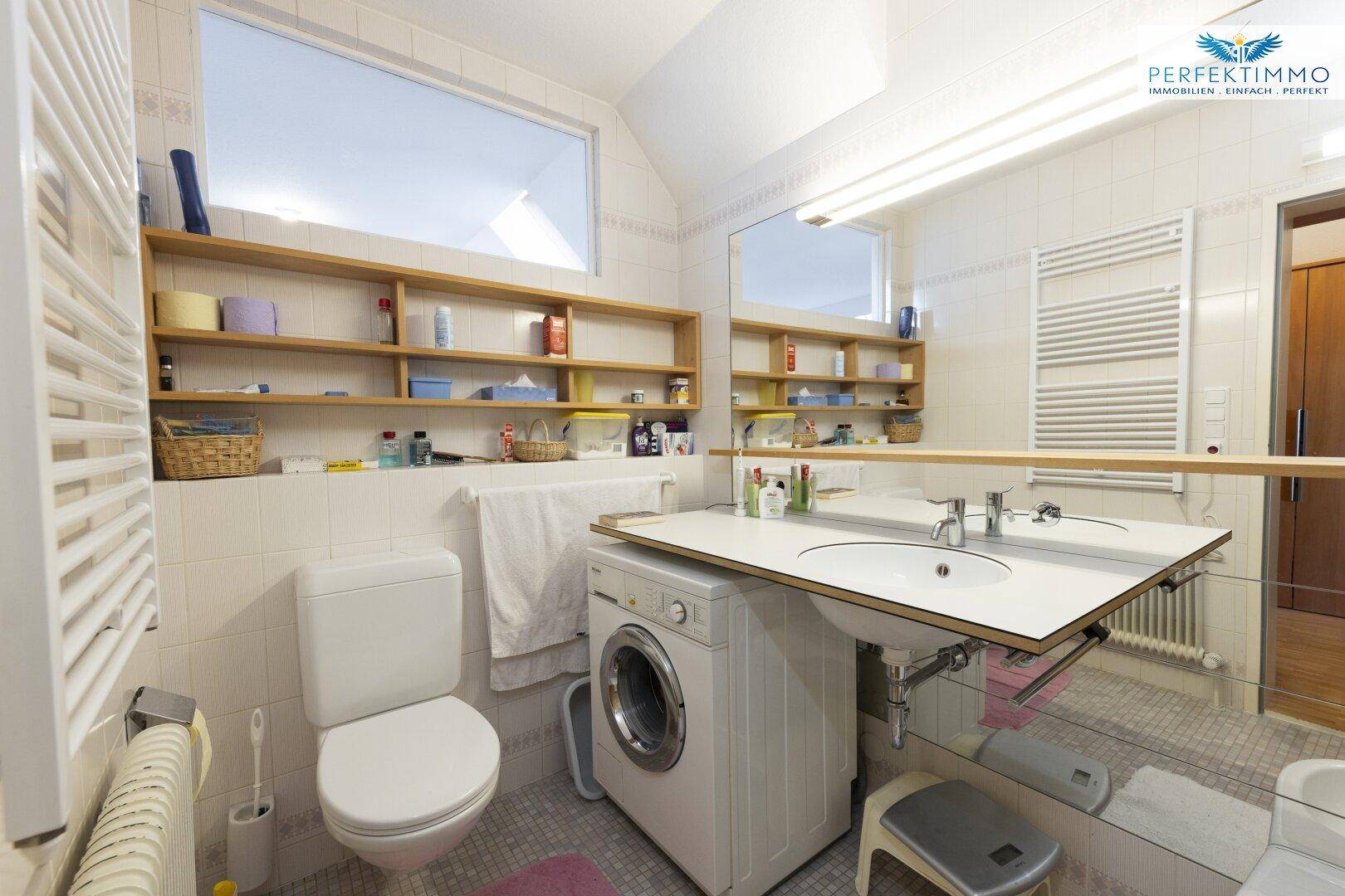 Helles Badezimmer mit Waschmaschine, Einzelwaschbecken und großem Spiegel.
