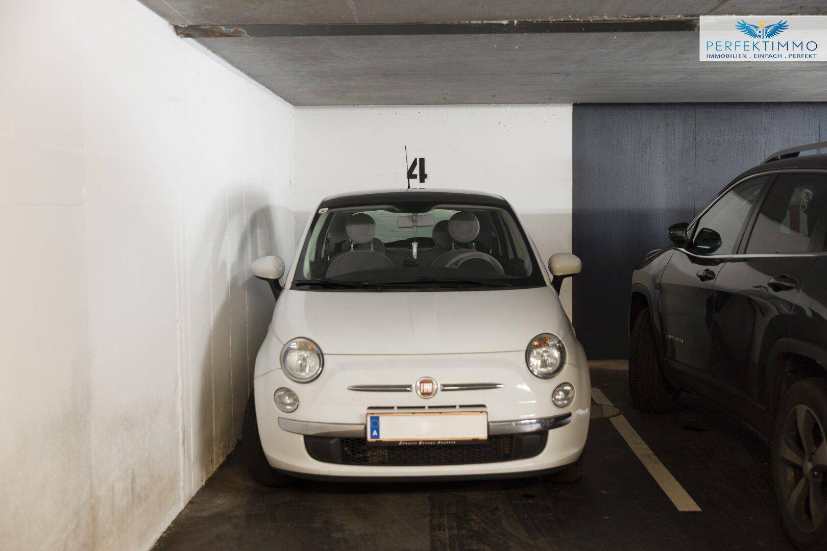 Tiefgaragenstellplatz mit einem geparkten Kleinwagen und Betonboden.