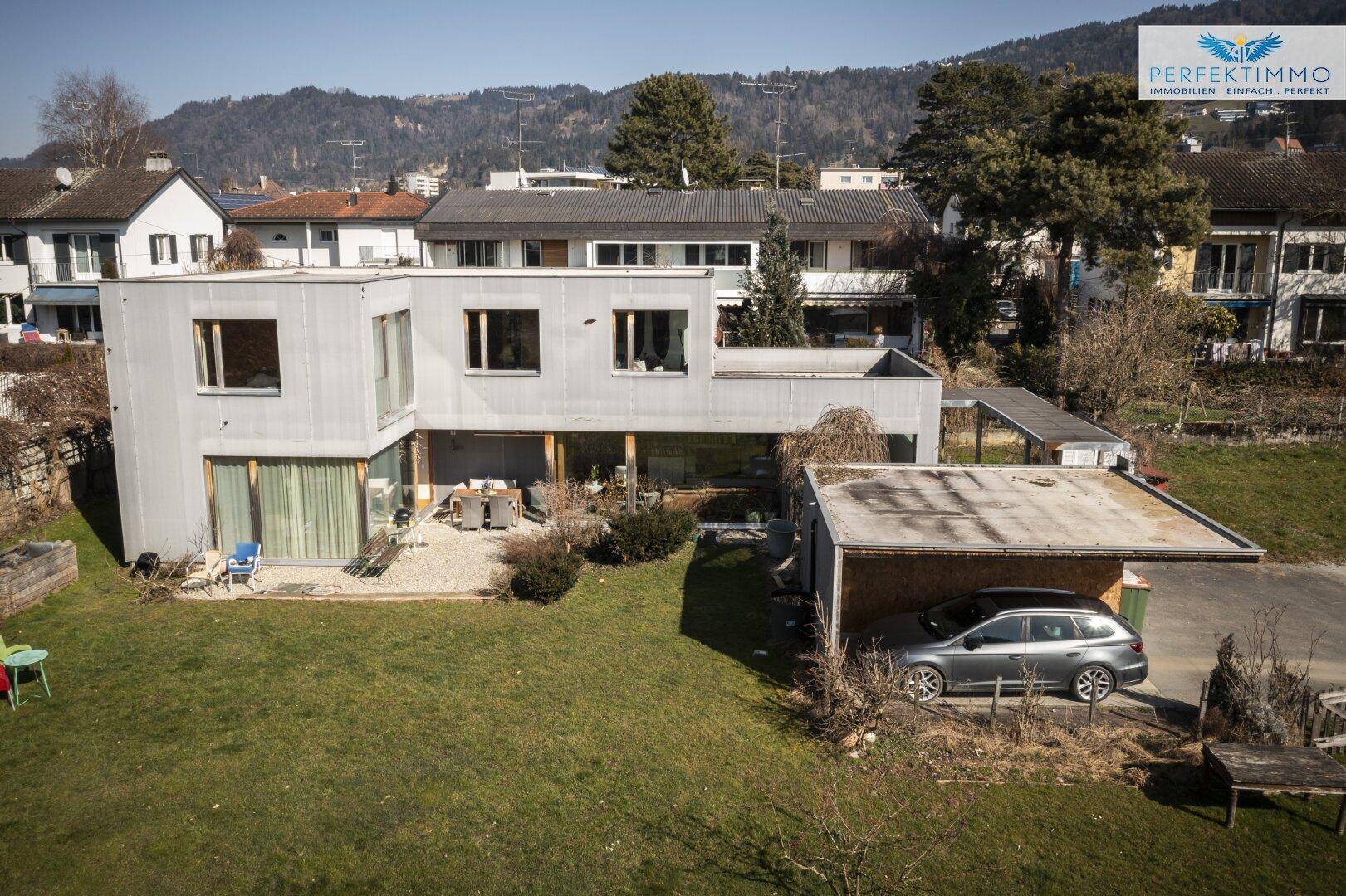 Ansicht des modernen Hauses mit großem Garten und Carport.