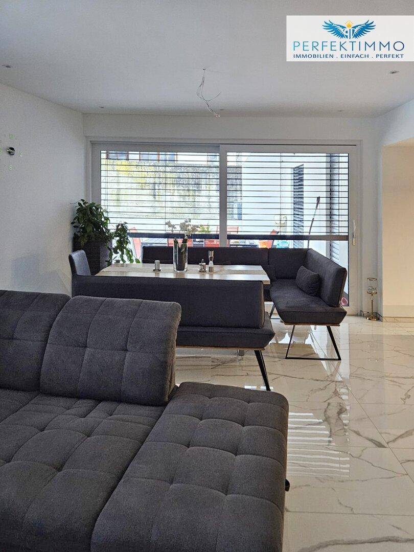 Heller Wohn- und Essbereich mit modernem Ecksofa und integrierter Sitzbank am Esstisch.