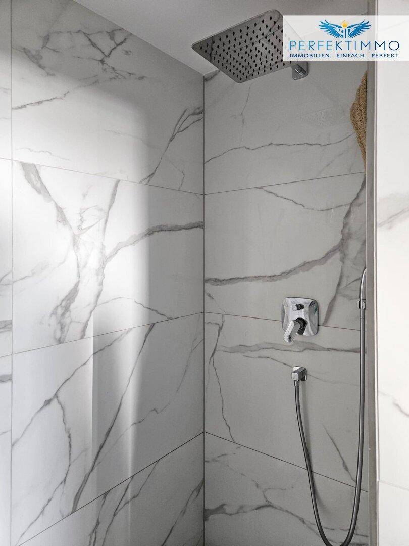 Geräumige begehbare Dusche mit Regenduschkopf und eleganten Marmorfliesen.