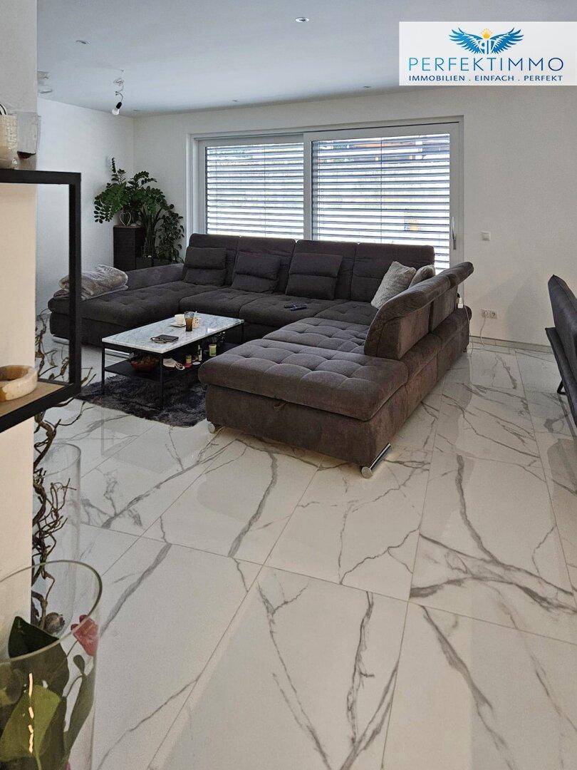 Modernes Wohnzimmer mit großem Ecksofa und elegantem Marmorfliesenboden.