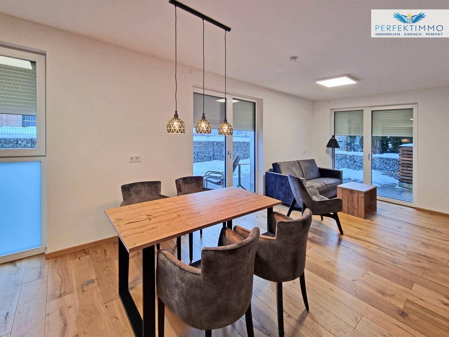 Heller Wohn- und Essbereich mit Holzboden, modernem Esstisch und Zugang zur Terrasse.