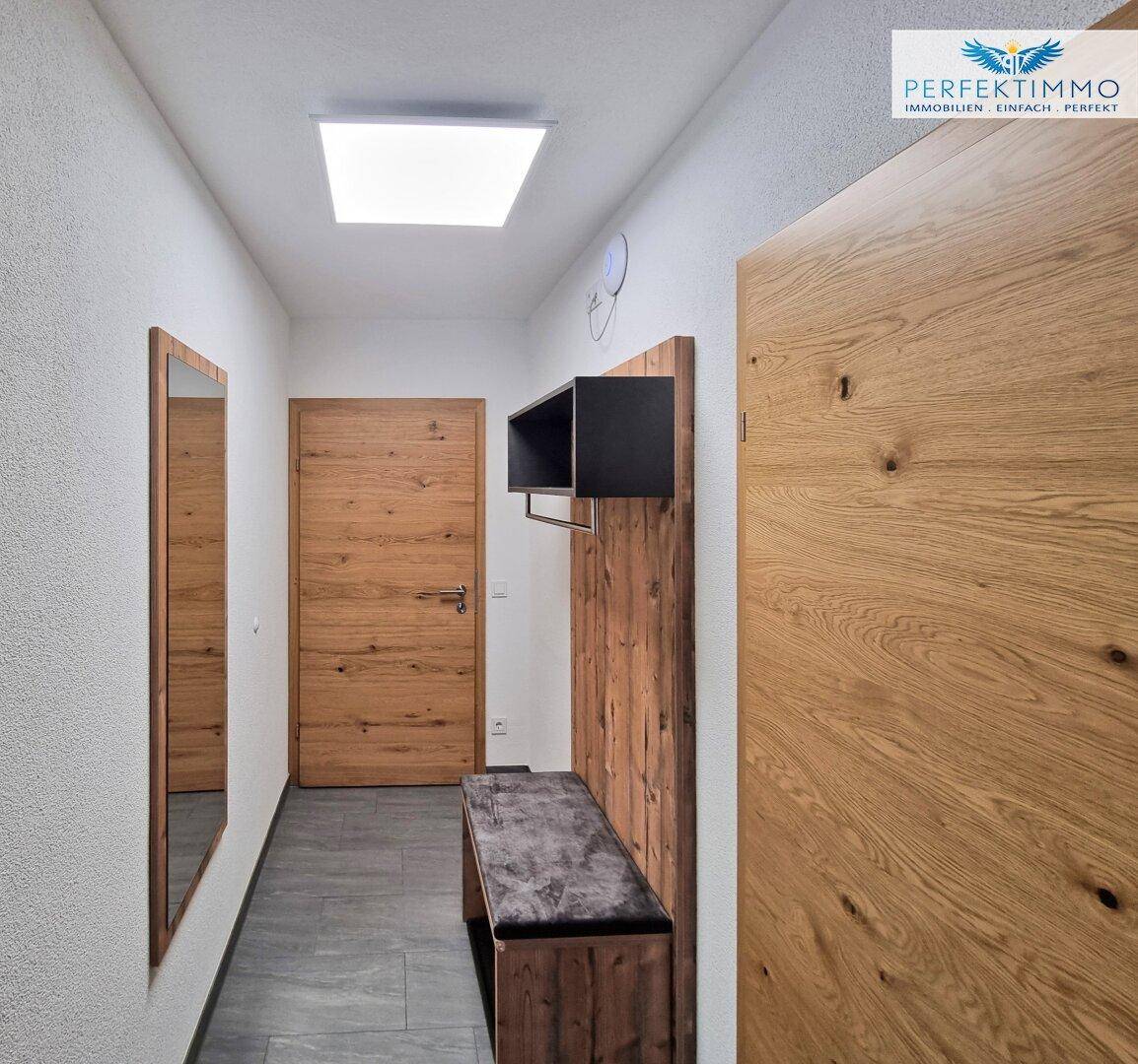Heller Flur mit Holzverkleidung, Spiegel und Sitzbank, ideal als Garderobenbereich.