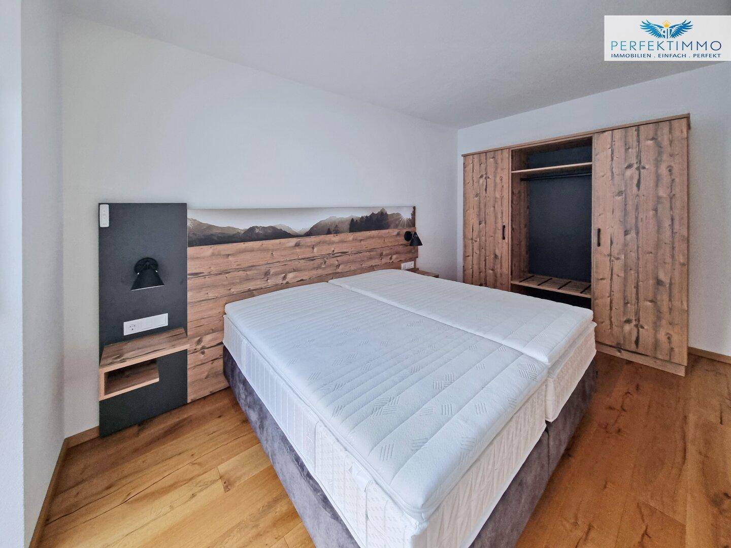 Gemütliches Schlafzimmer mit Doppelbett, Holzboden und integriertem Kleiderschrank im alpinen Stil.