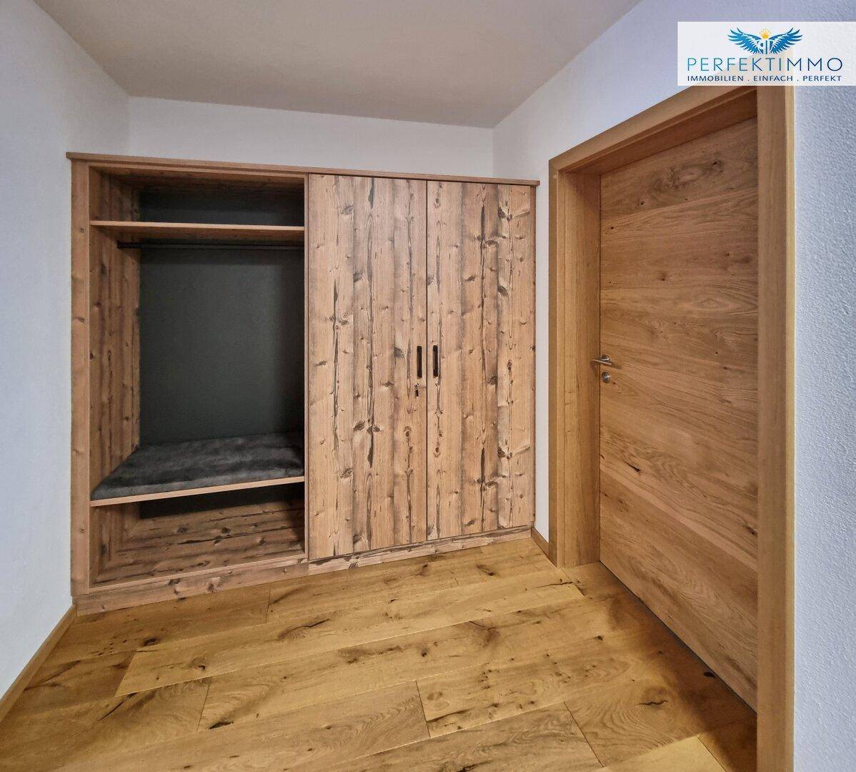 Eingangsbereich mit maßgefertigtem Holzschrank und Holzboden, bietet viel Stauraum.