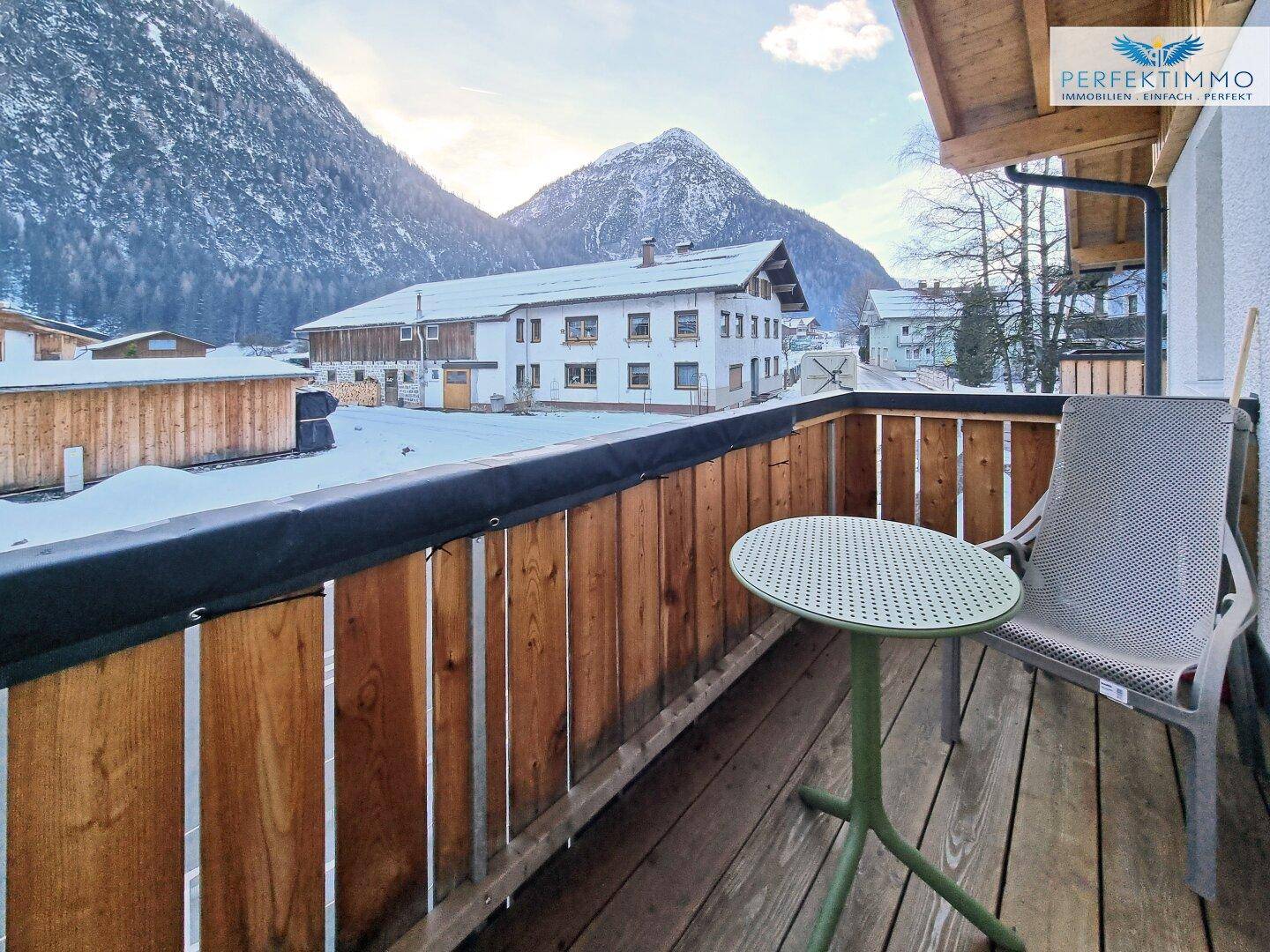 Kleiner Balkon mit Sitzgelegenheit und Blick auf die verschneite Berglandschaft.