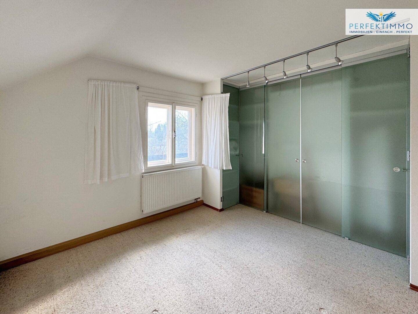Schlafzimmer mit Teppichboden und integriertem Kleiderschrank mit Milchglas-Schiebetüren.