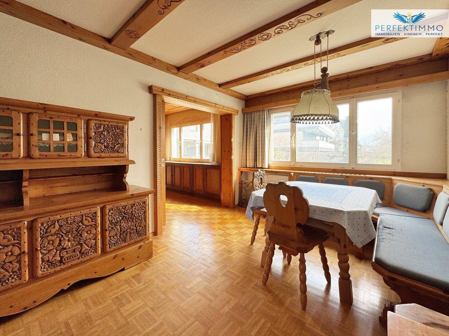 Traditioneller Essbereich mit Holzbalkendecke, Parkettboden und Blick in den angrenzenden Raum.