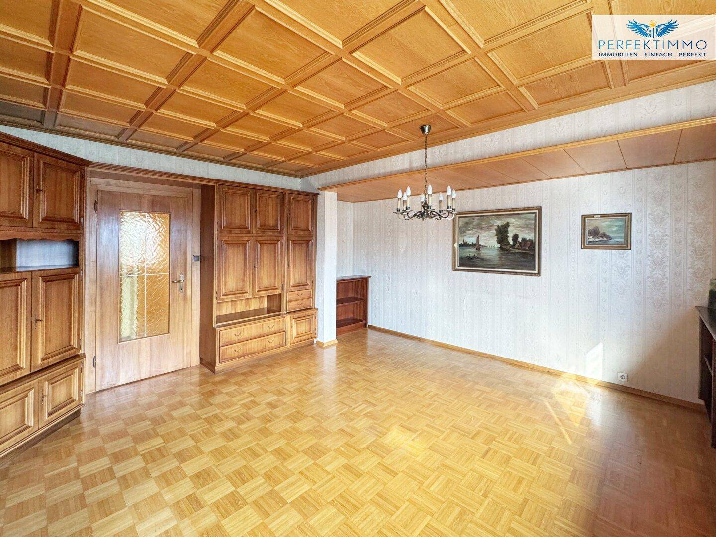 Helles Wohnzimmer mit Holzkassettendecke, Parkettboden und traditionellen Holzmöbeln.