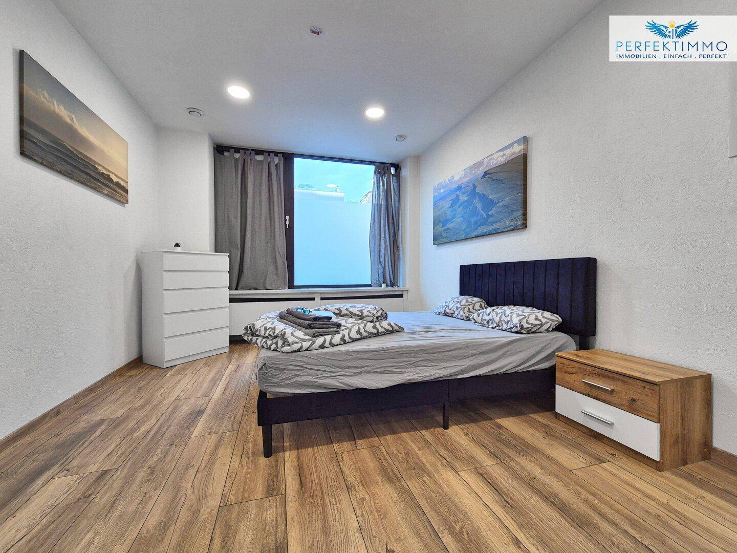 Gemütliches Schlafzimmer mit Holzboden, Doppelbett und großem Fenster.