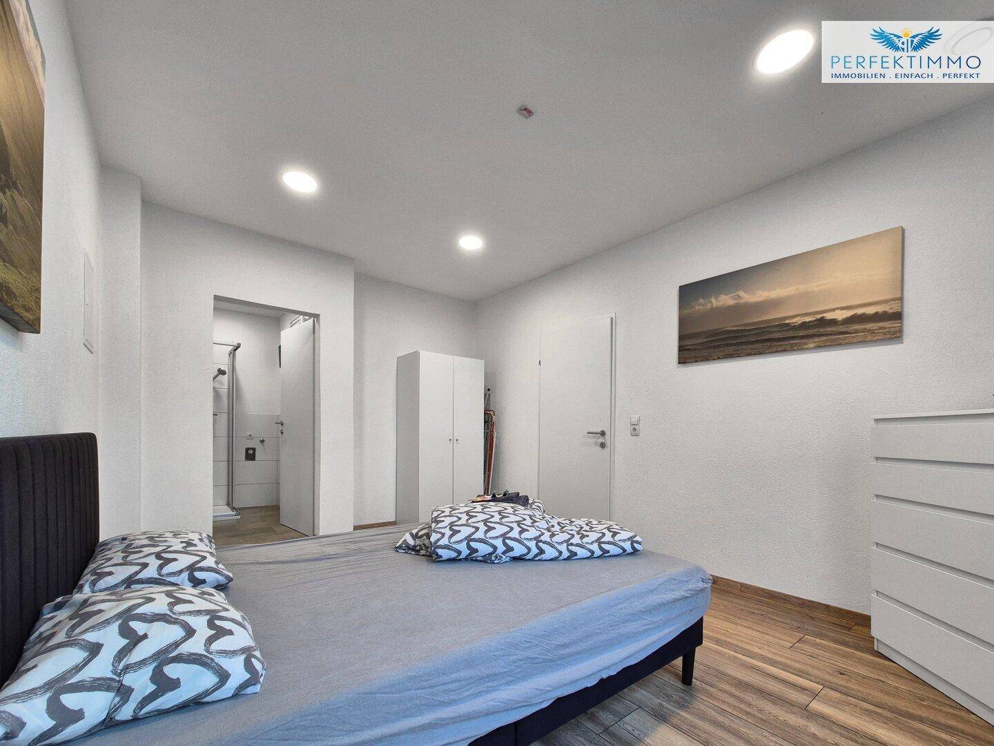 Schlafzimmer mit Holzboden, Doppelbett und direktem Zugang zum Badezimmer.