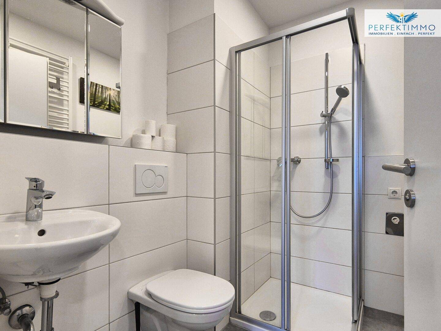 Modernes Badezimmer mit Duschkabine, wandhängendem WC und Waschbecken.