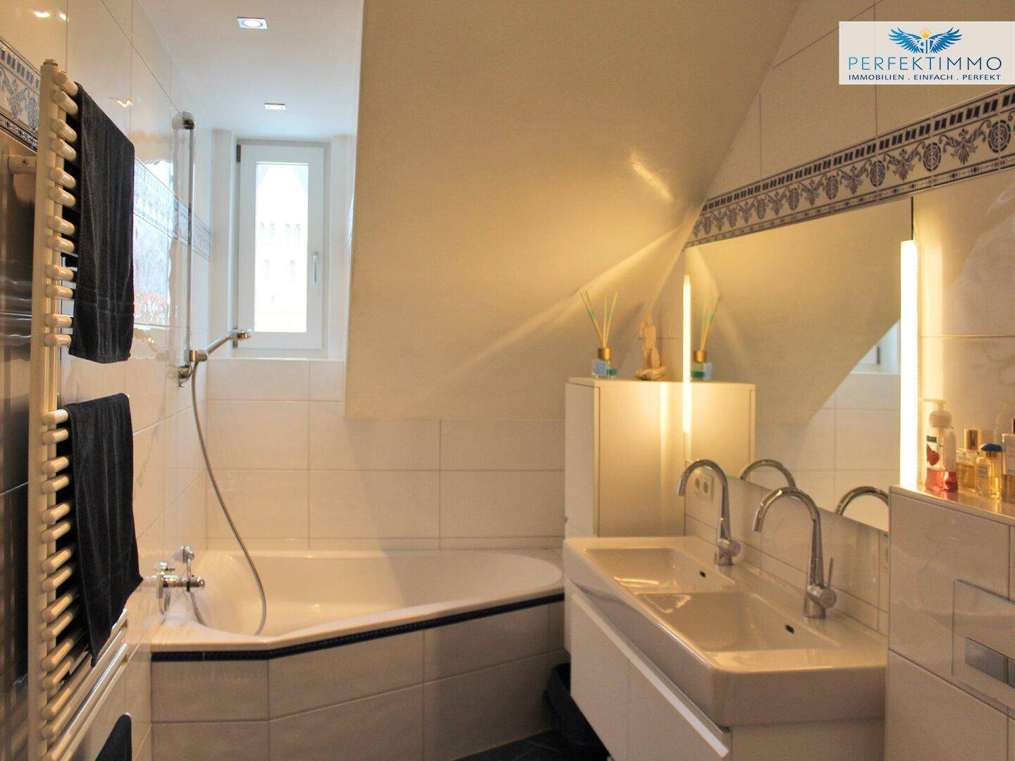 Helles Badezimmer im Dachgeschoss mit Eckbadewanne, Doppelwaschbecken und Fenster.