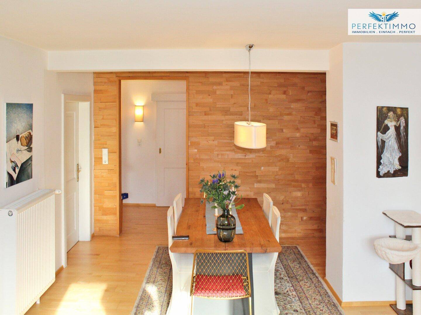 Gemütlicher Essbereich mit Holztisch, Holzvertäfelung und Zugang zu einem weiteren Raum.