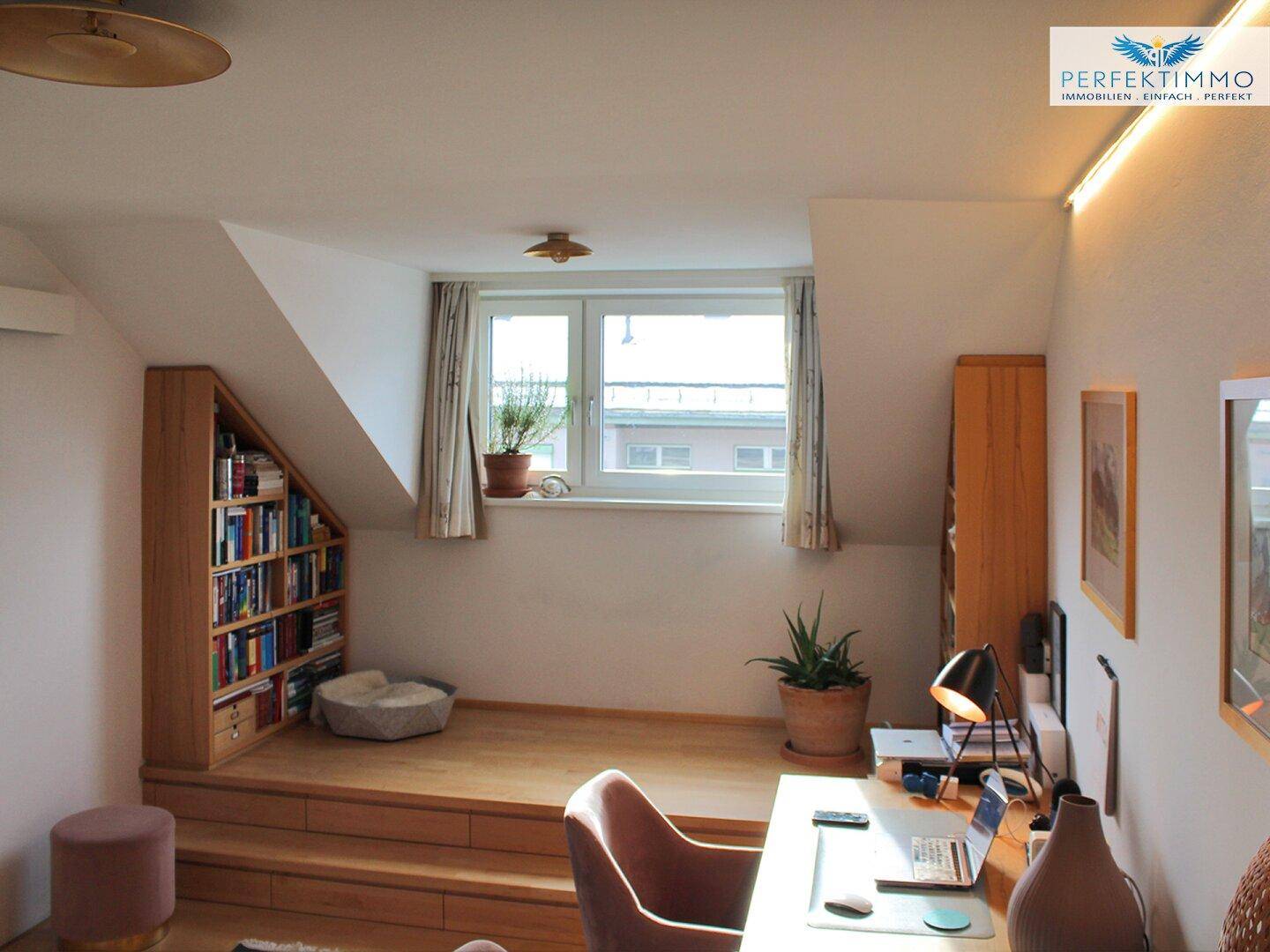 Ruhiges Arbeitszimmer im Dachgeschoss mit eingebauten Regalen und Fensterblick.