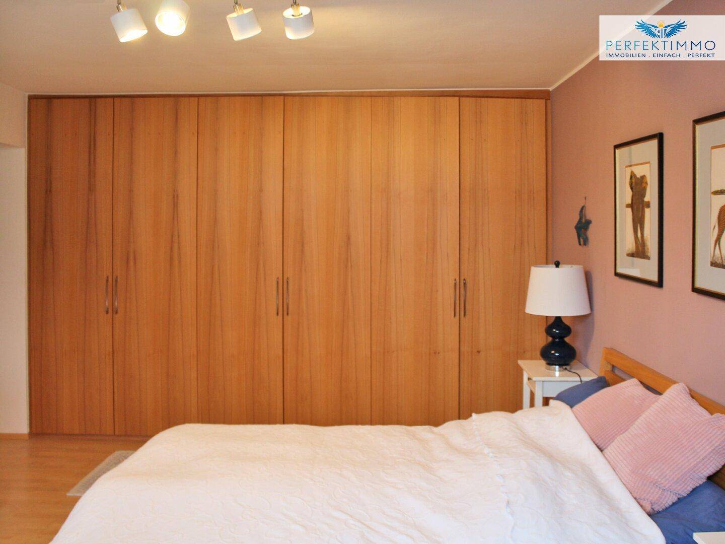 Schlafzimmer mit großen Einbauschränken aus Holz und gemütlicher Atmosphäre.