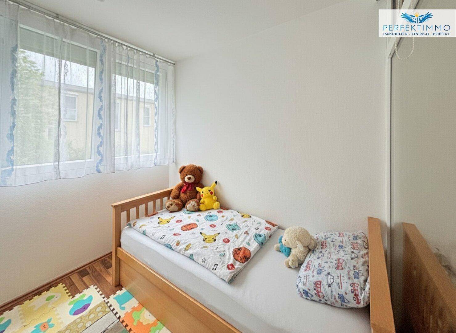 Kinderzimmer mit Einzelbett, Spielzeug und Fenster, hell und freundlich gestaltet.
