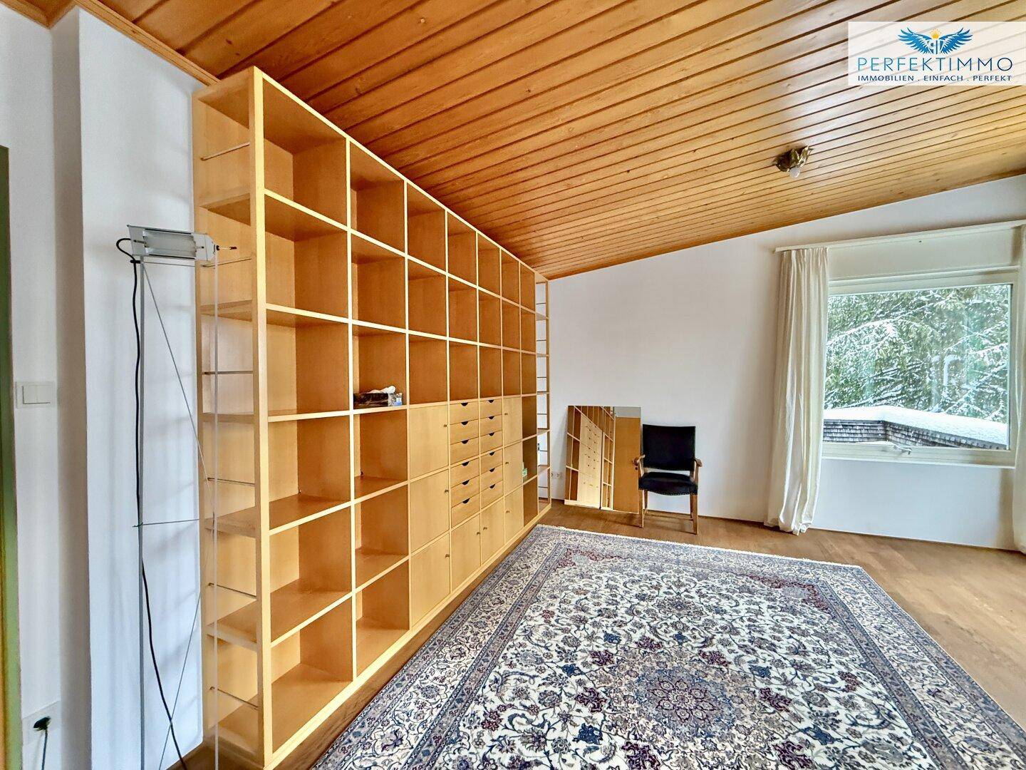 Wohnzimmer mit großer Holzregalwand, Holzboden und Teppich, bietet viel Stauraum.