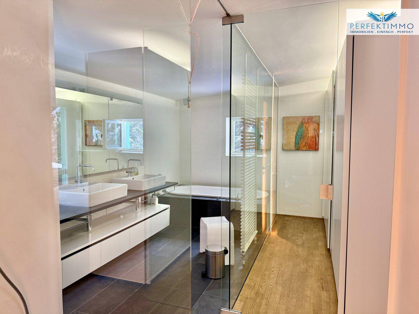 Modernes Badezimmer mit Doppelwaschbecken, Badewanne und separater Glasdusche, hell und geräumig.