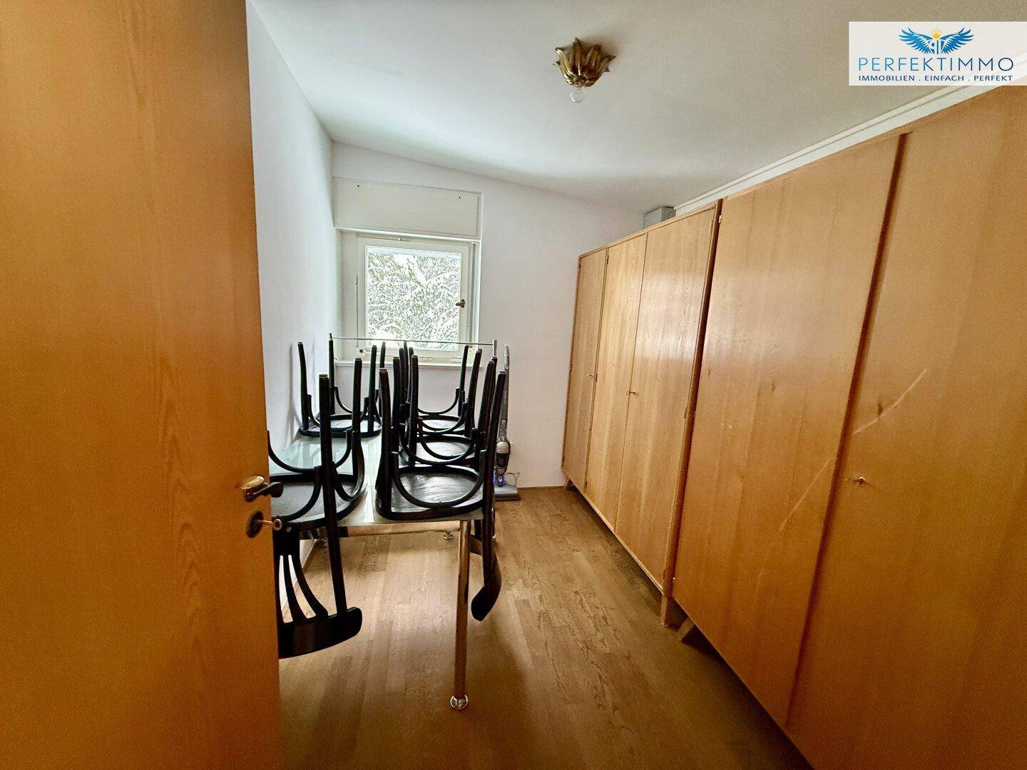 Praktischer Abstellraum mit Holzschränken und einem Tisch, ideal für Lagerung und Arbeitsfläche.