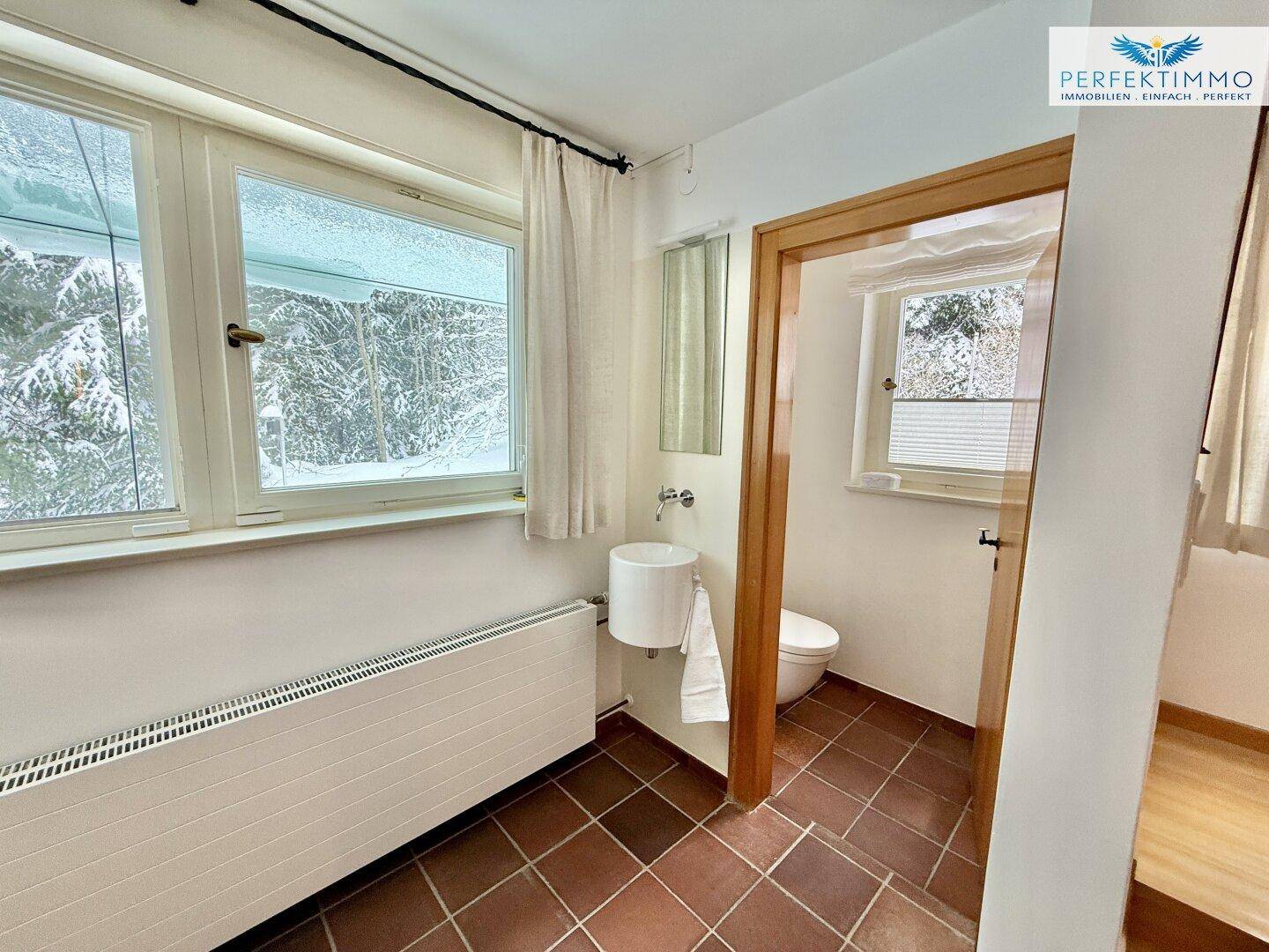 Kleines Gäste-WC mit Terrakotta-Fliesenboden, Fenster und Heizkörper, funktional und hell.