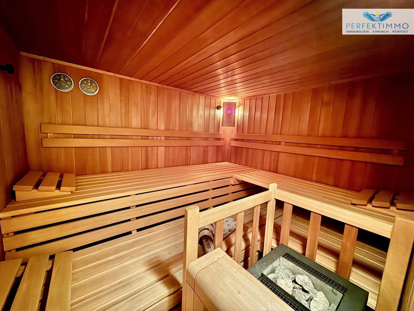 Geräumige Holzsauna mit mehreren Bänken und einem Saunaofen, bereit zur Nutzung.