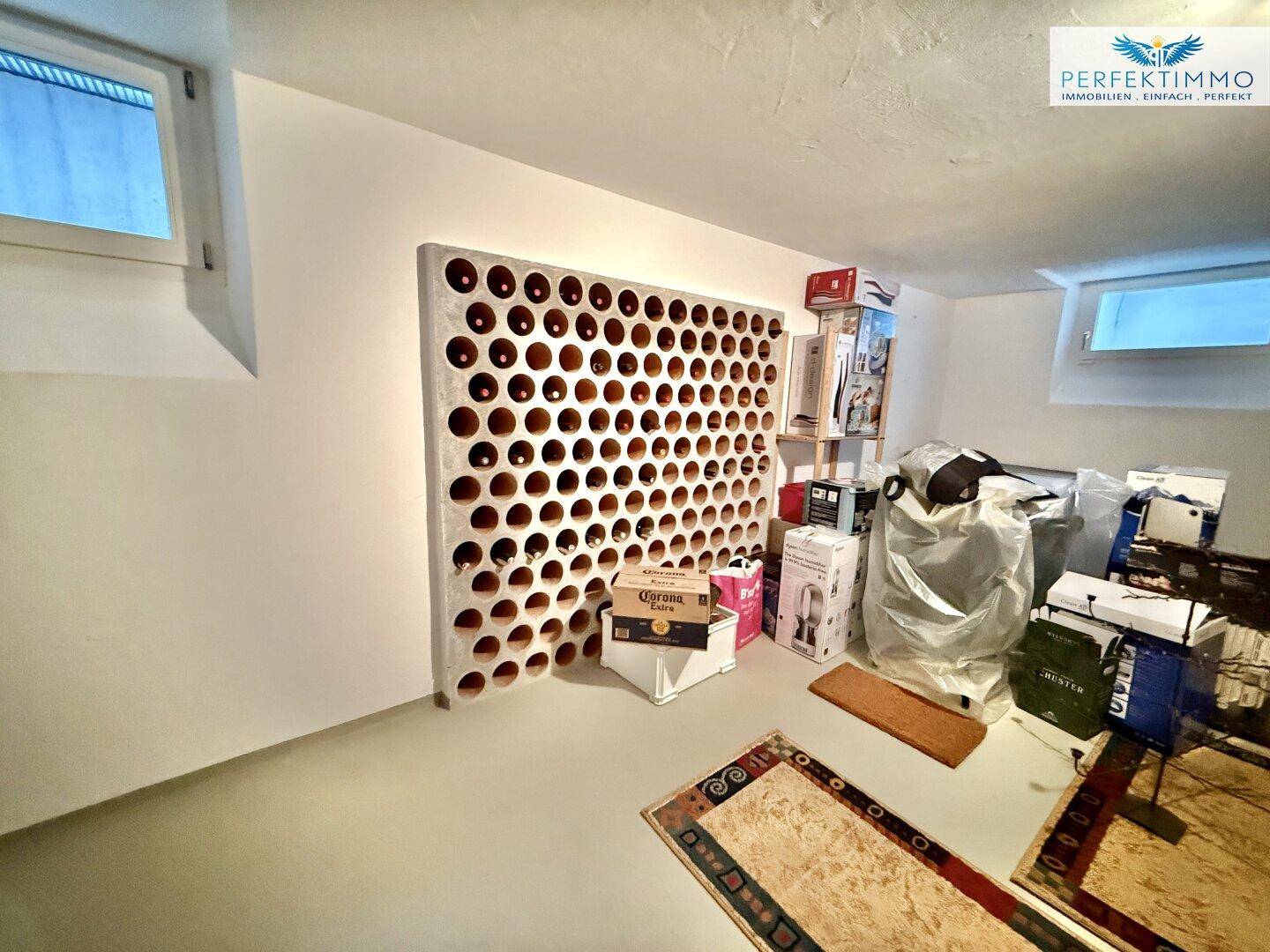 Kellerraum mit integriertem Weinregal und Stauraum, beleuchtet durch kleine Fenster.