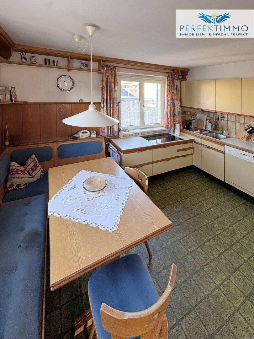 Gemütliche Wohnküche mit Essecke, Holzvertäfelung und traditionellen Fliesen.