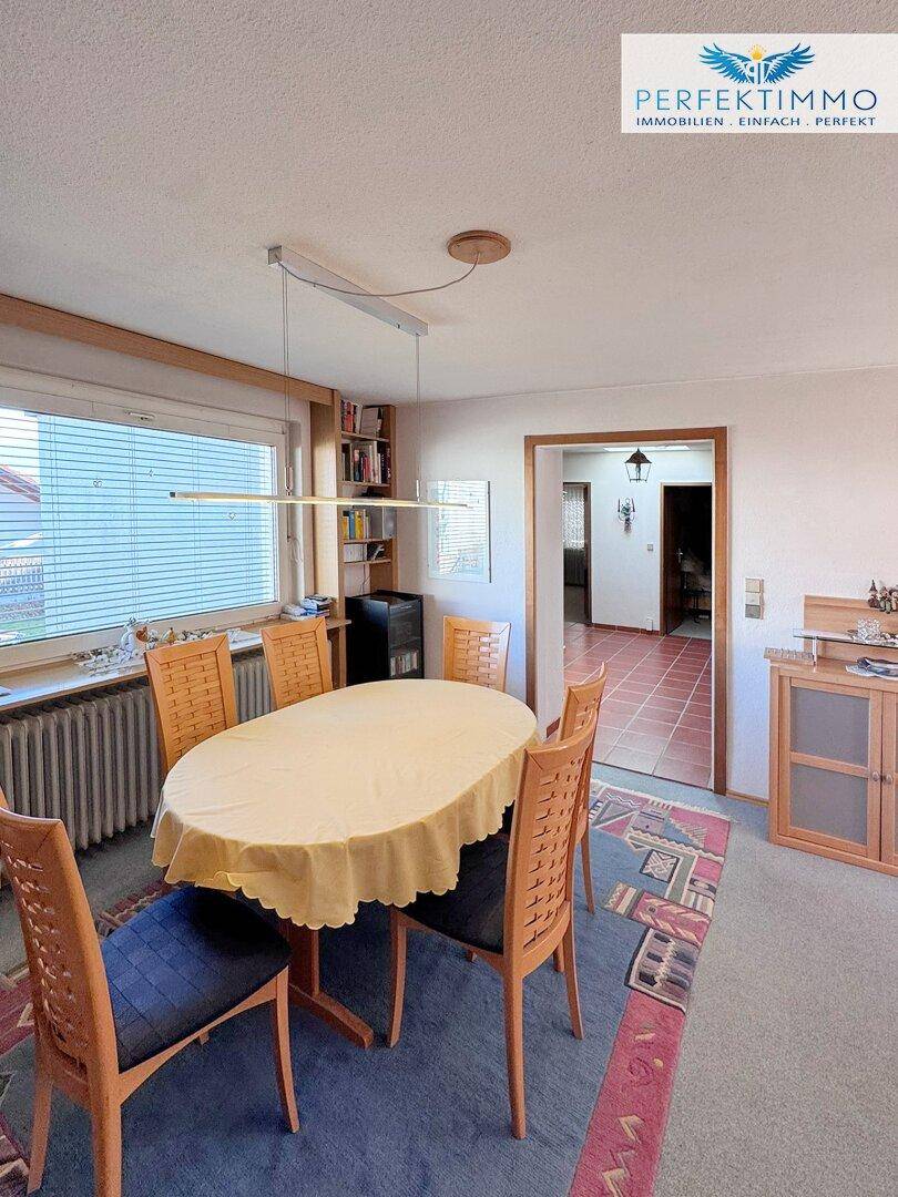 Separater Essbereich mit großem Fenster, Holztisch und Teppichboden.
