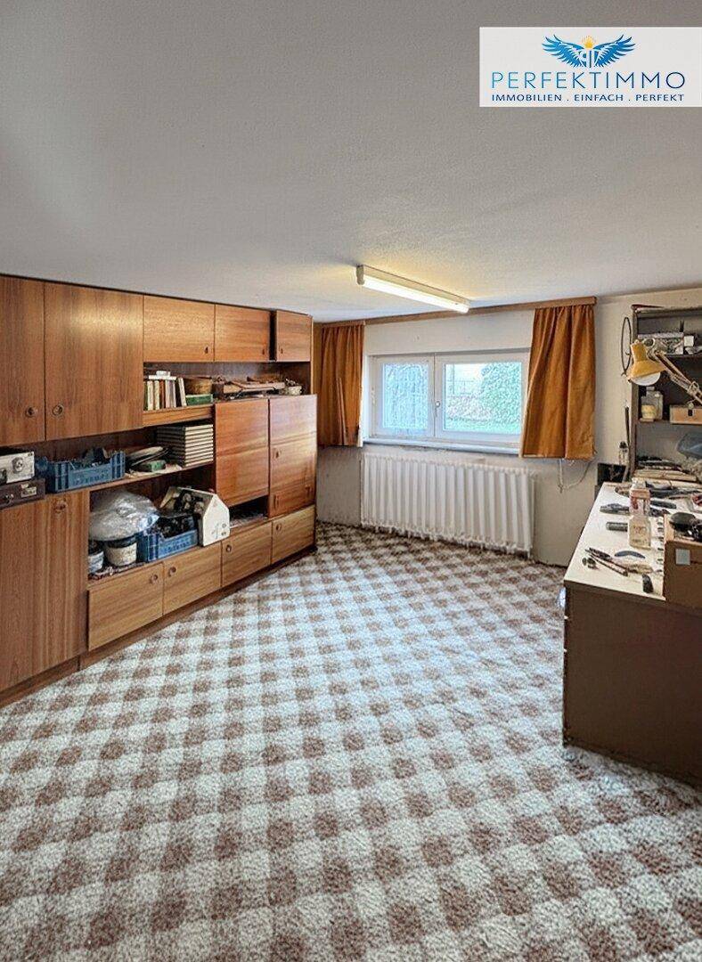 Hobbyraum im Keller mit Teppichboden, Einbauschränken und Fenster.