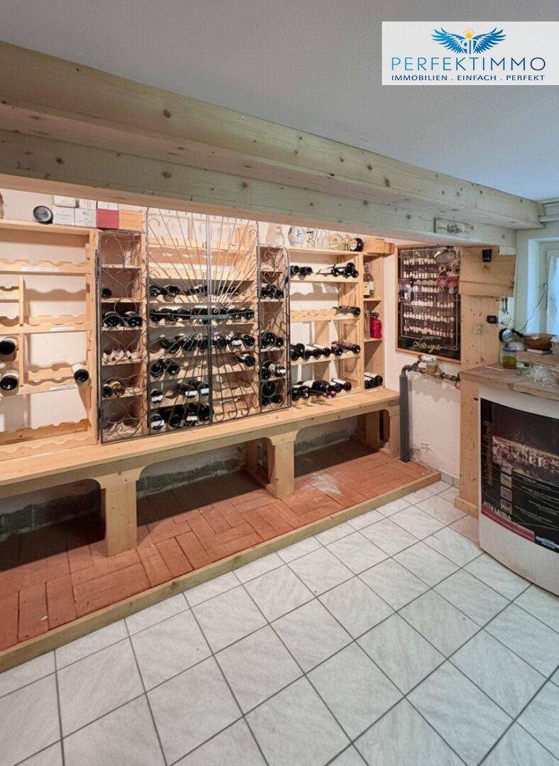 Gut ausgestatteter Weinkeller mit Holzregalen und Fliesenboden.