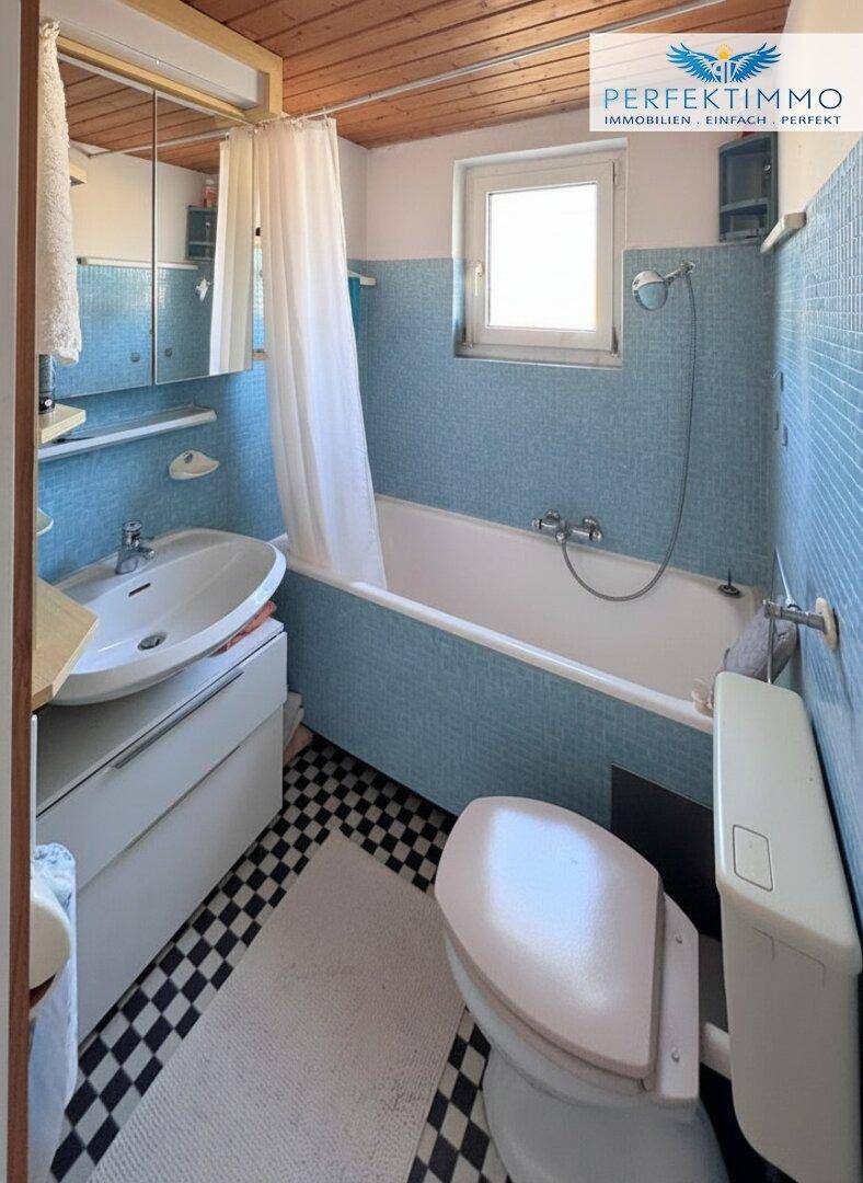 Badezimmer mit Badewanne, Waschbecken und blau-weiß kariertem Fliesenboden.