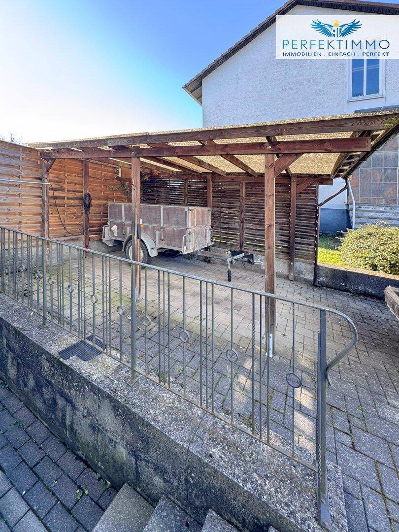 Überdachter Stellplatz oder Carport aus Holz für Fahrzeuge oder Anhänger.