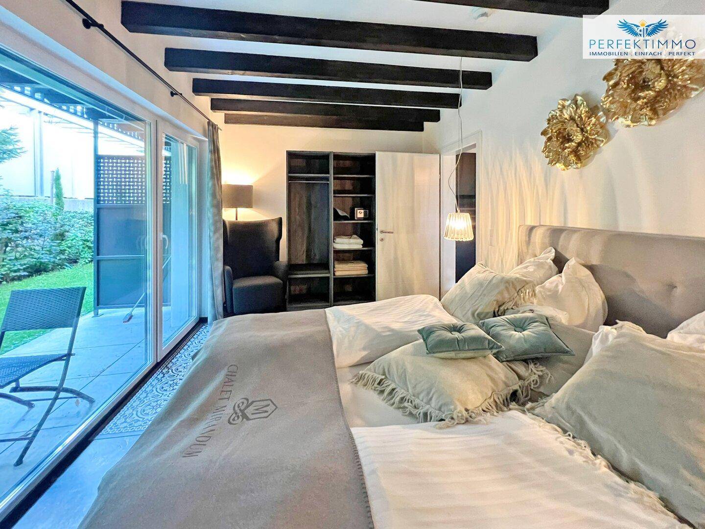 Schlafzimmer mit Doppelbett, Einbauschrank und Zugang zu einer privaten Terrasse im Freien.