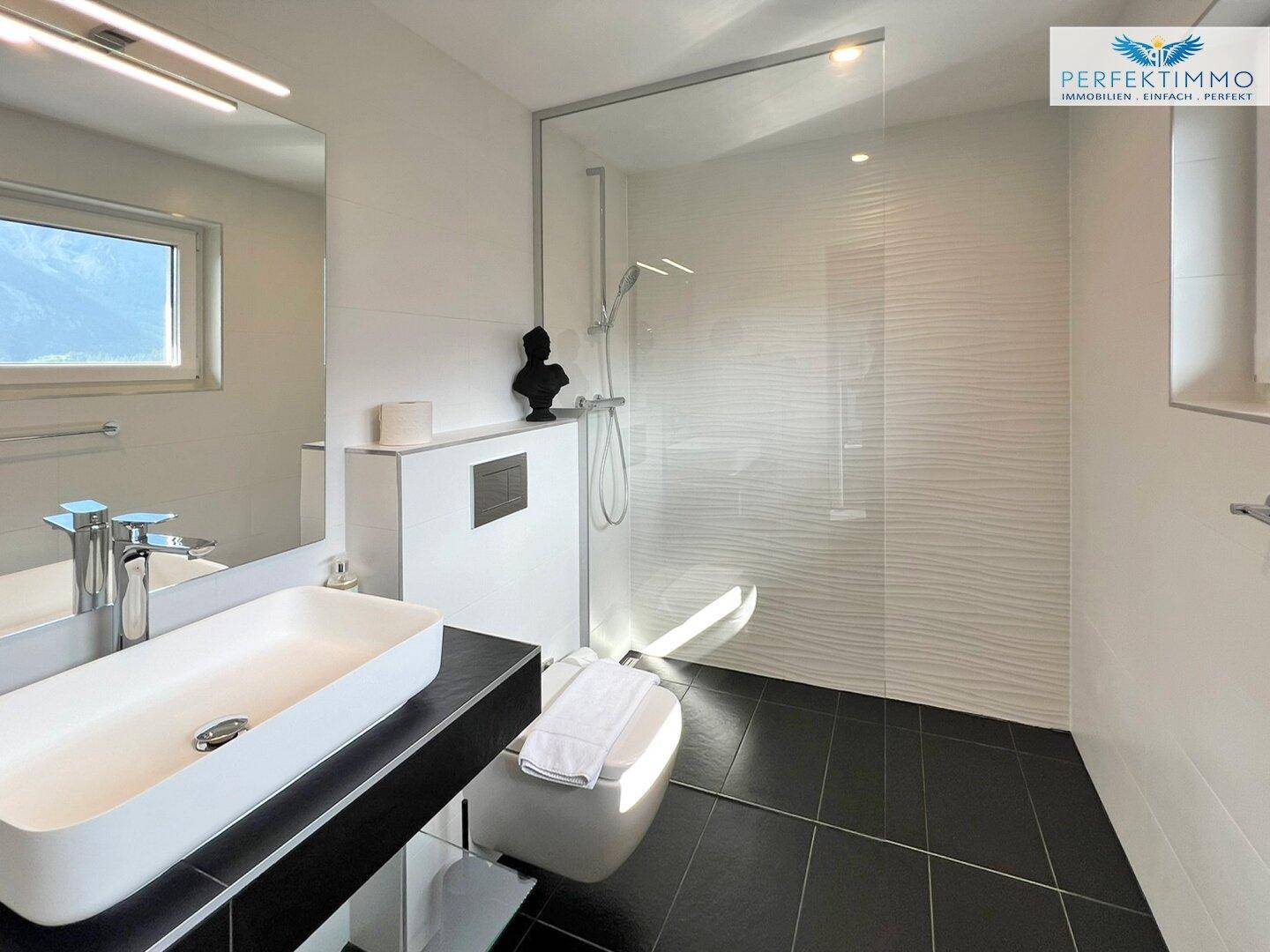 Helles Badezimmer mit moderner Dusche, Wand-WC und Fenster mit Blick auf die Landschaft.