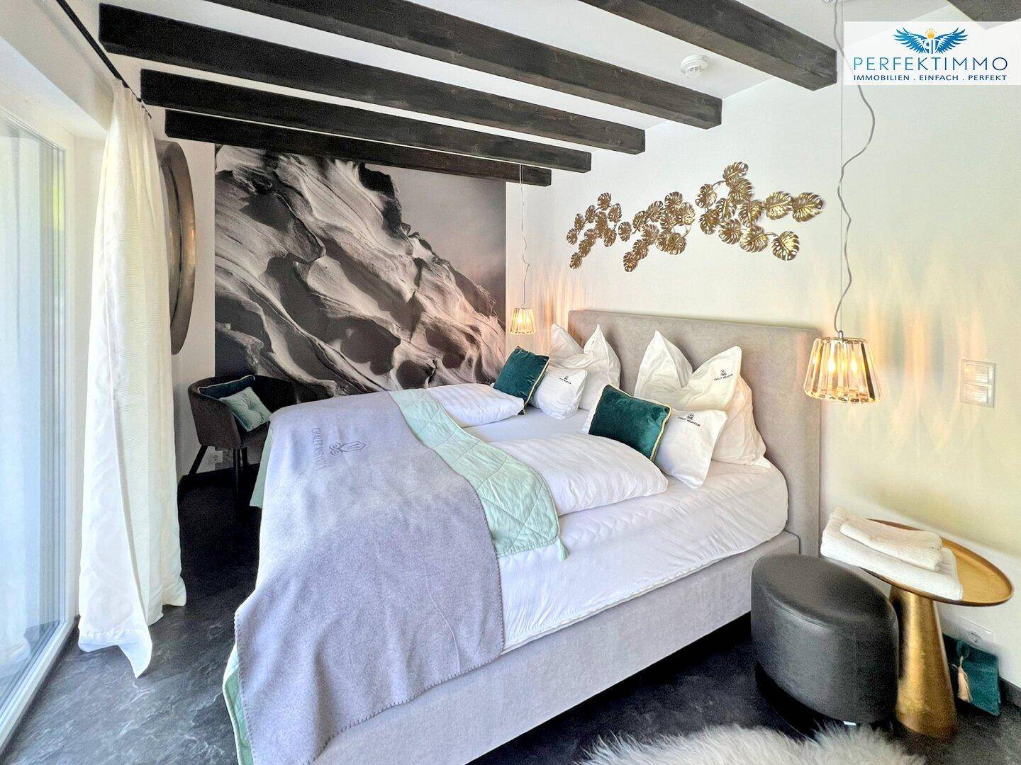 Gemütliches Schlafzimmer mit großem Bett, Holzbalken und stilvoller Wanddekoration.