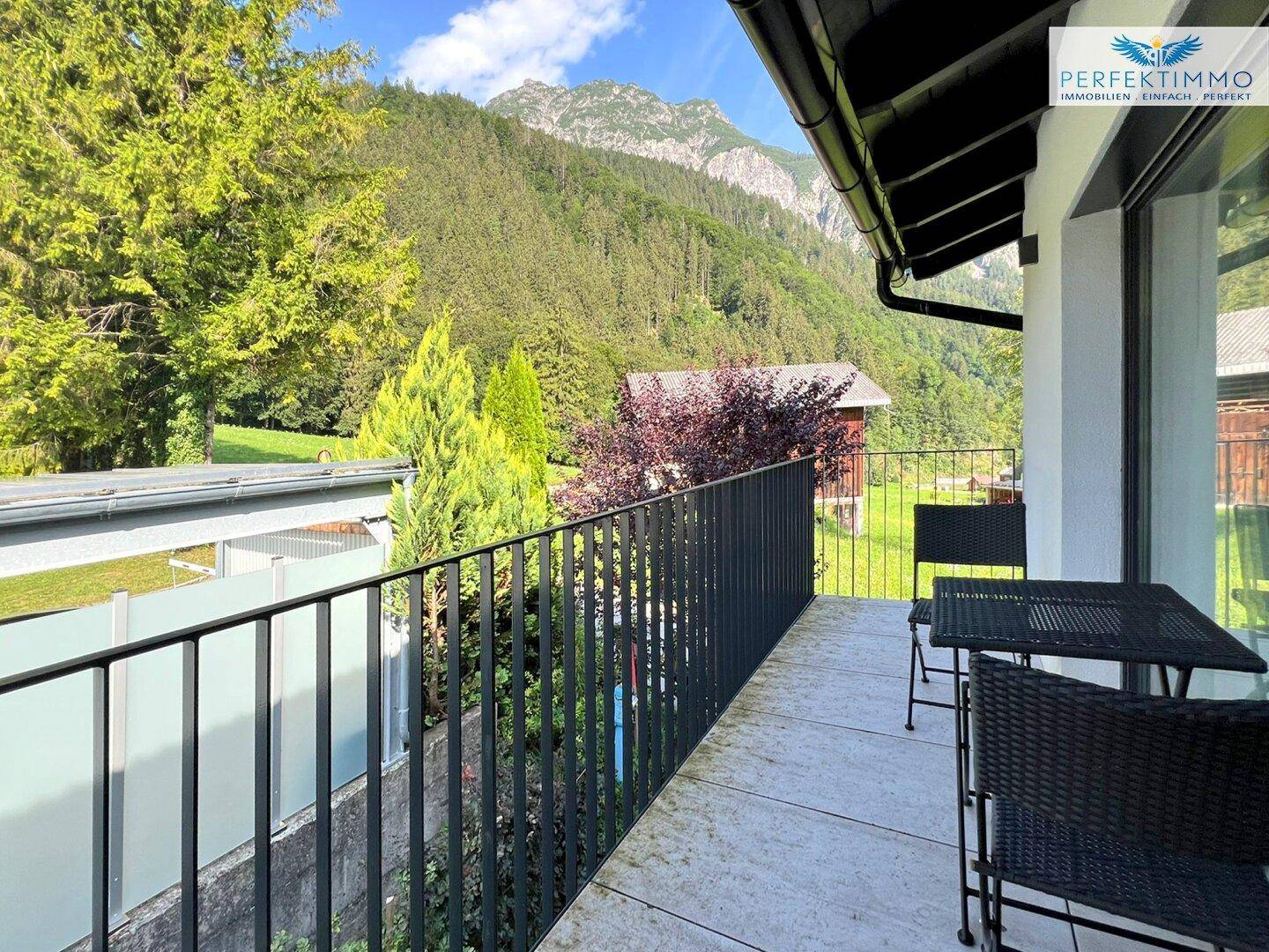 Balkon mit Sitzgelegenheiten und weitem Blick auf die umliegende Berglandschaft und Natur.