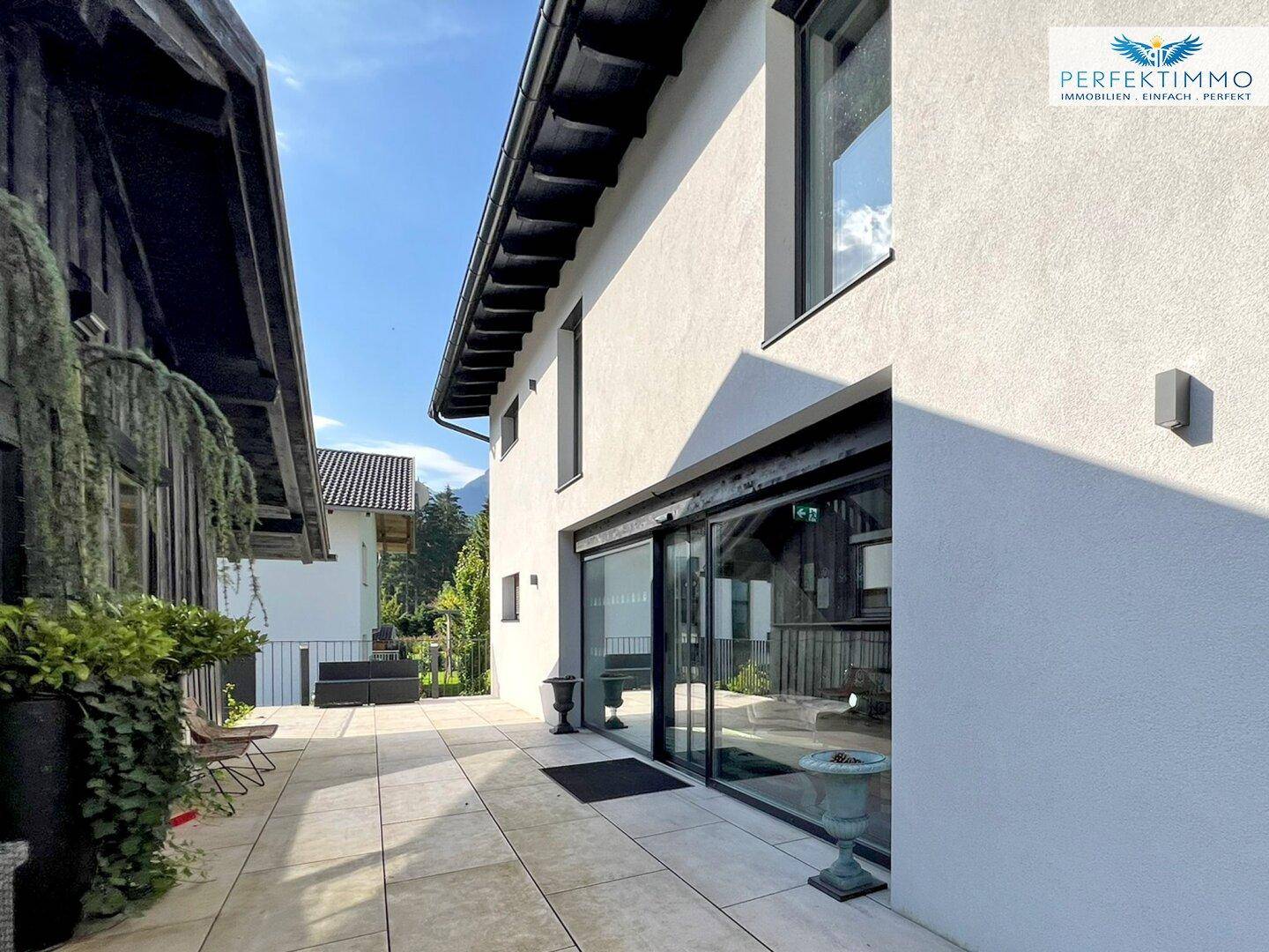 Breite Terrasse mit großen Glasfronten, die den Innenbereich mit der Natur verbinden.