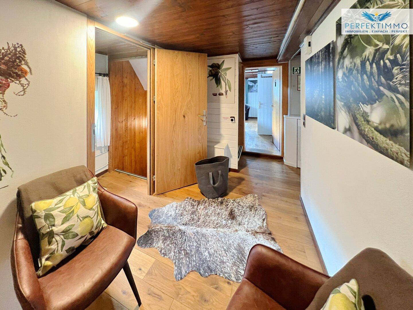 Gemütlicher Flur mit Holzboden, Ledersesseln und rustikaler Dekoration.