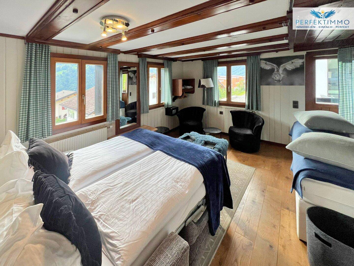 Geräumiges Schlafzimmer mit Doppelbett, Holzboden und Blick ins Grüne.