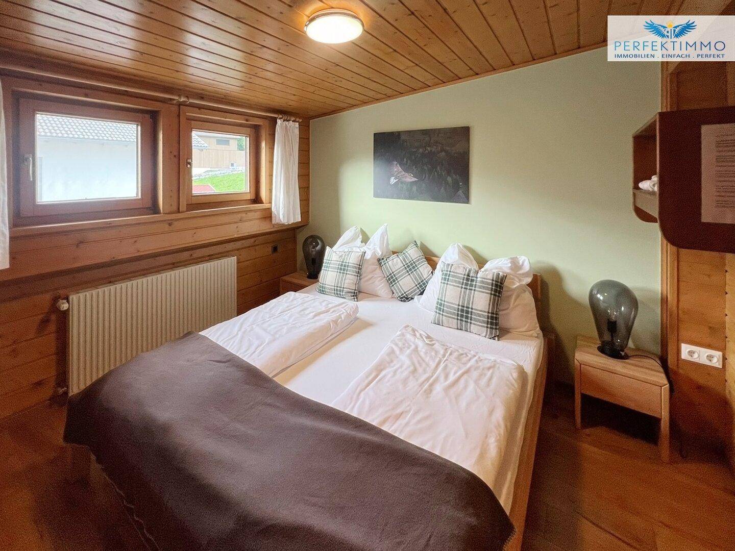 Gemütliches Schlafzimmer mit Doppelbett, Holzboden und grünen Akzenten.